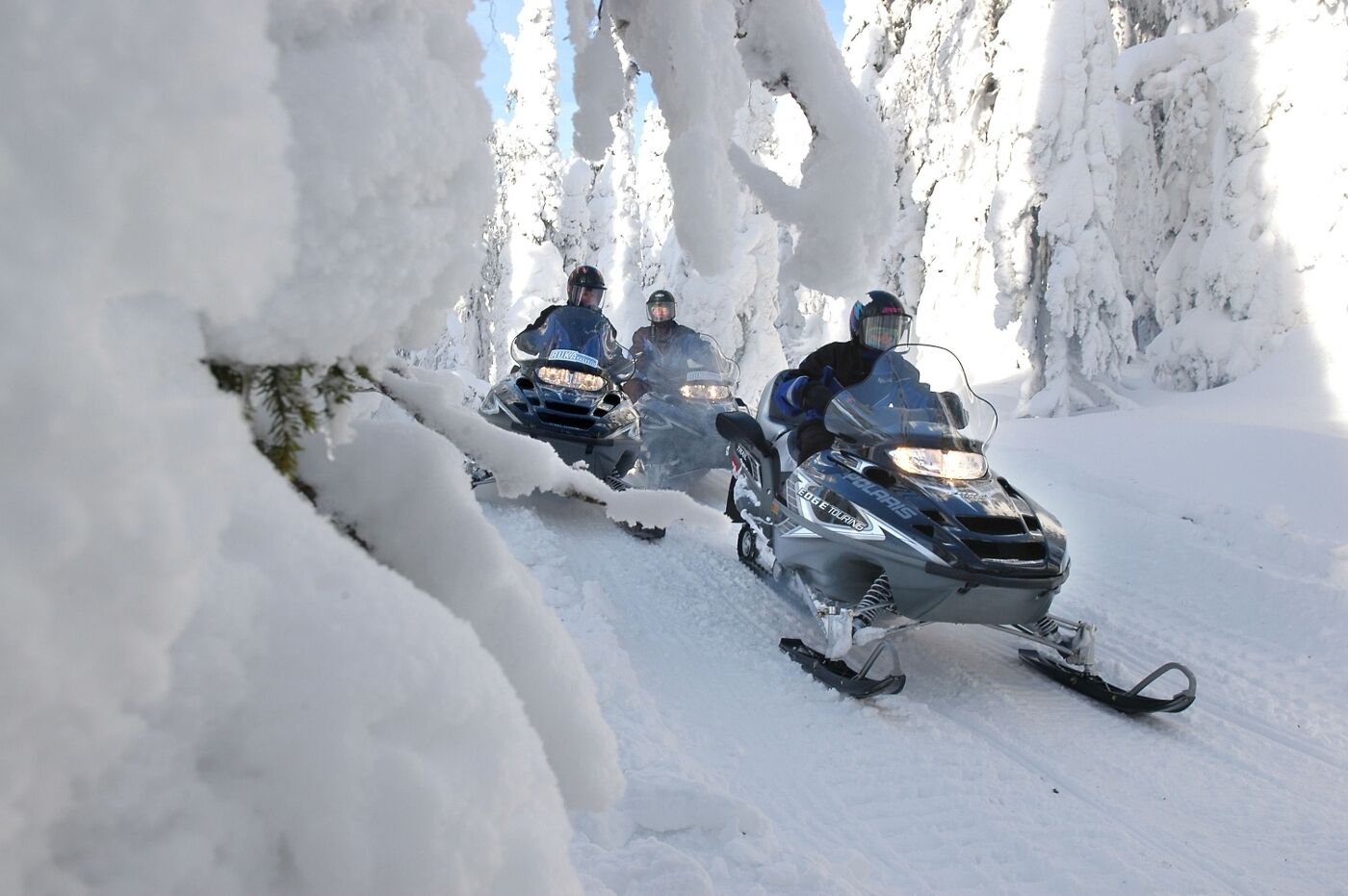 Three snowmobiles on a snowy path.