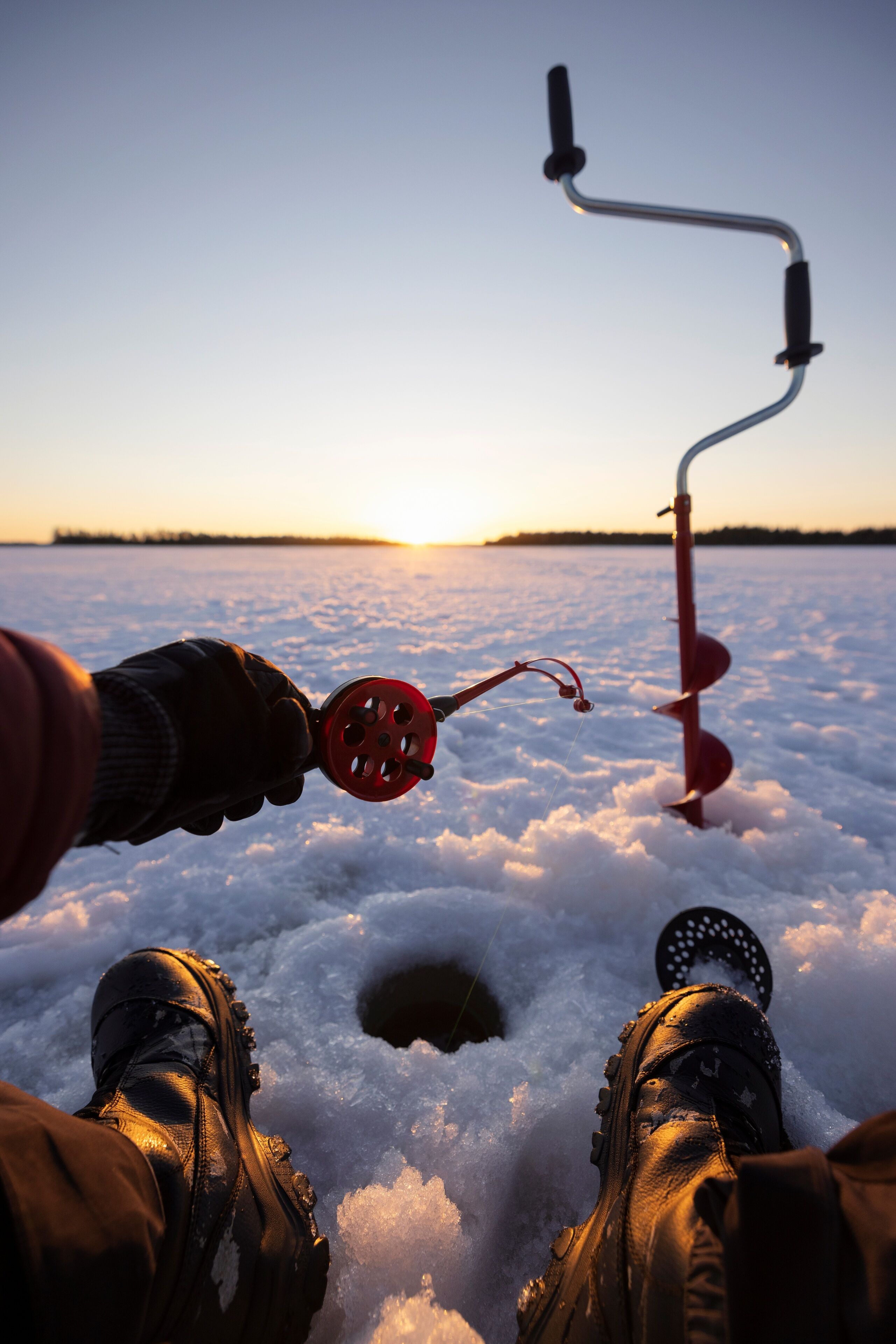 A person standing in snow with a fishing rod and reel.