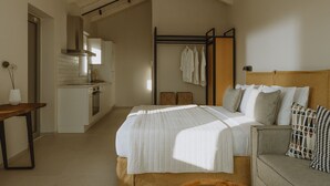 Un dormitorio con cama, mesitas de noche, cabecero de madera y vista a una cocina con un tendedero.