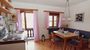 A kitchen with a sink, stove, and dining area with chairs and a table. - Ferienwohnung Bergblick (Oberaudorf)