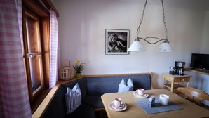 A cozy room with a wooden bench, a table with a cup and saucer, a hanging light fixture, and a framed picture on the wall. - Ferienwohnung Bergblick (Oberaudorf)