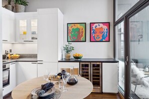 Enjoy meals and gatherings in this stylish kitchen and dining area, featuring a central island, vibrant artwork, and a wine cooler.