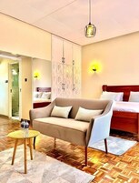 Habitación de hotel con sofá, cama, armario y una mesita redonda con botellas de agua.