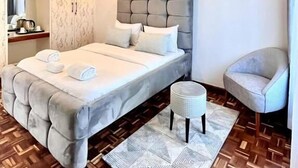 Un dormitorio moderno con una cama grande, una mesita de noche, una silla y un armario.