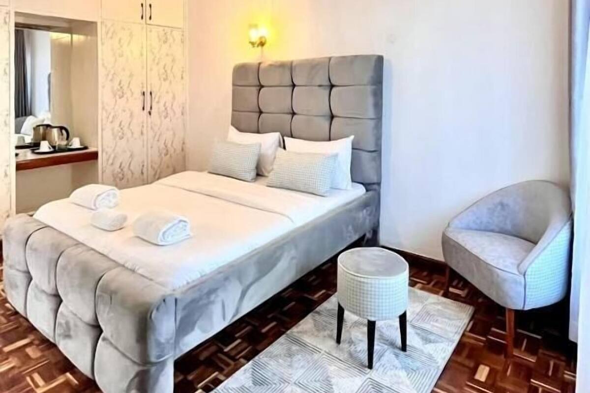 Une chambre à coucher moderne avec un grand lit, une table de chevet, une chaise et une armoire.