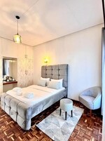 Un dormitorio moderno con una cama grande, una mesita de noche, una silla y un armario.