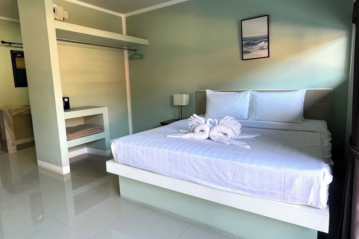 Una habitación de hotel con cama, mesita de noche, un cuadro en la pared y estantería empotrada.