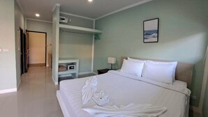 A hotel room with a large bed, a bedside table, a nightstand, a wardrobe, and a painting on the wall. - J & Ariya Hotel (Koh Samui)