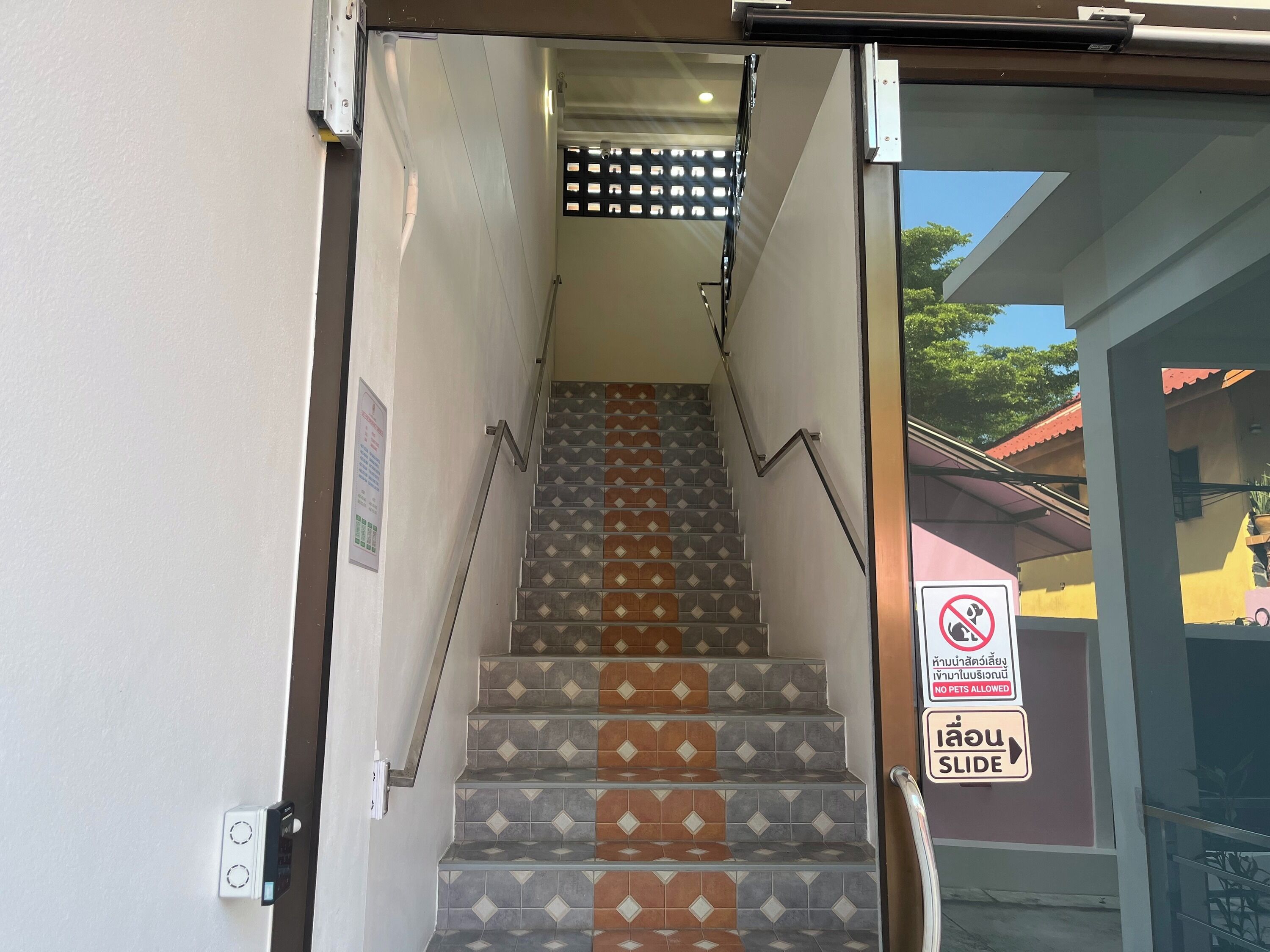 Una escalera con barandilla y un letrero que indica 'No se admiten mascotas'.