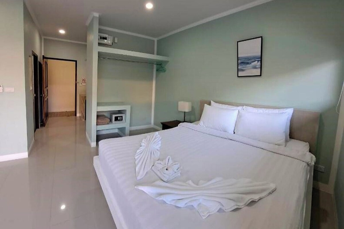 A hotel room with a large bed, a bedside table, a nightstand, a wardrobe, and a painting on the wall.