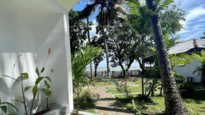 Un camino que lleva a un edificio blanco con vista al mar y palmeras.