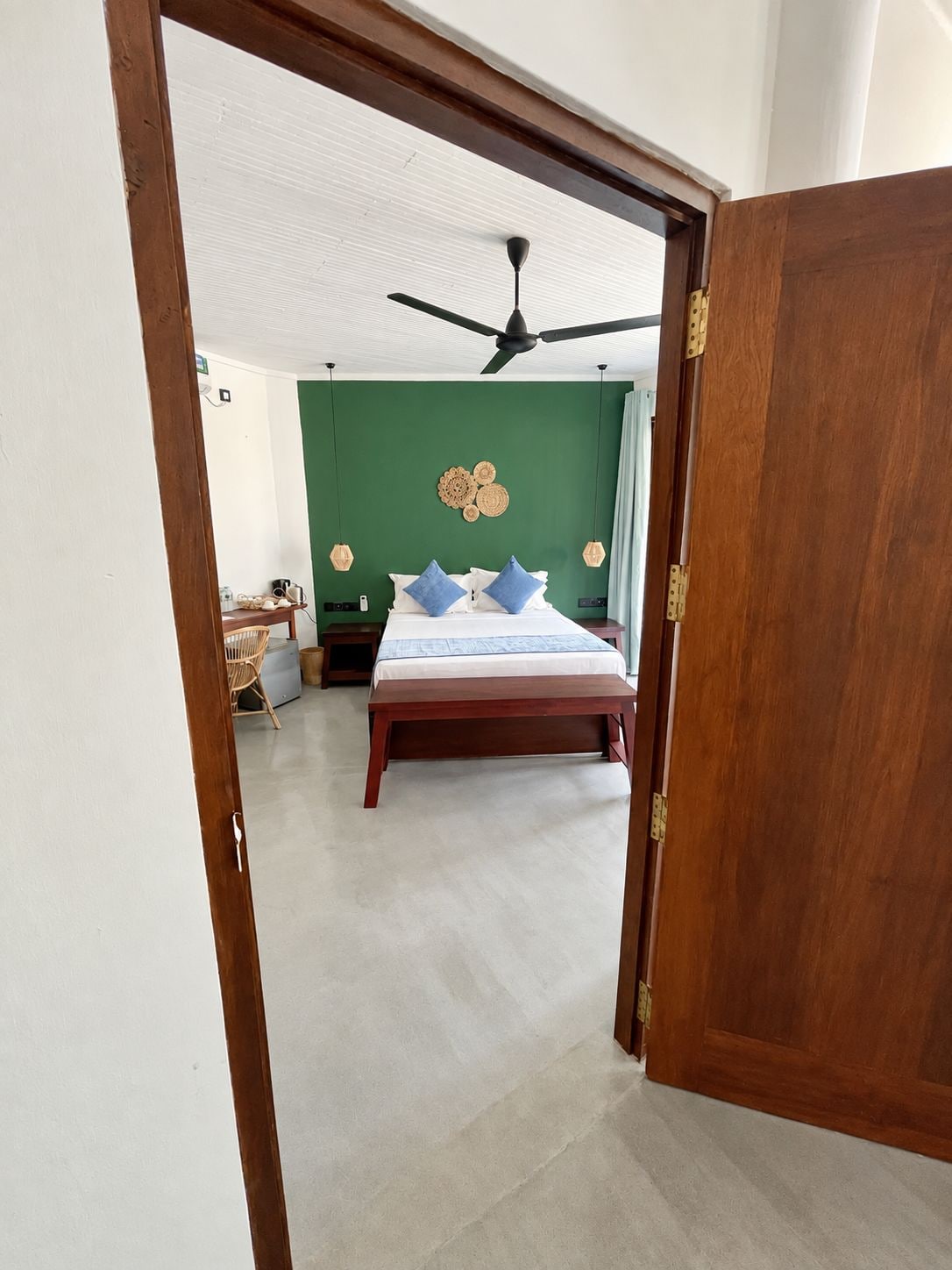 A bedroom with a bed, a ceiling fan, and a green wall.