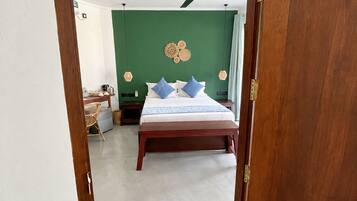 A bedroom with a bed, a ceiling fan, and a green wall.