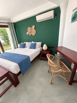 Een slaapkamer met een bed, een bureau, een stoel, een airconditioning en een decoratieve wandversiering.
