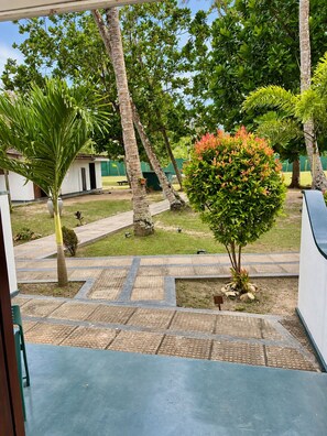 Un patio con palmeras, un pequeño jardín y un camino empedrado.