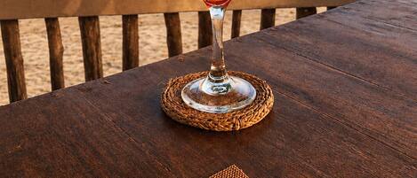 A glass of iced beverage on a wooden table with a view of the ocean and a flag in the background.