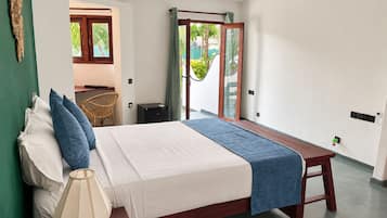 Habitación de hotel con cama, mesita de noche, lámpara y vistas al exterior a través de una puerta corrediza.