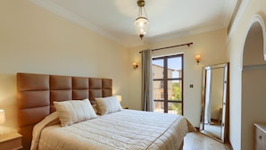 Et soveværelse med en stor seng, et natbord, en kommode og et spejl.