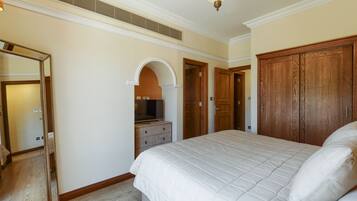 A bedroom with a large bed, wooden wardrobe, and a mirror.