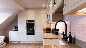 A modern kitchen with white cabinetry, a built-in oven, and a marble countertop. - Longshaw Loft - Family 3 Bed Apt WiFi & Parking (Buxton)