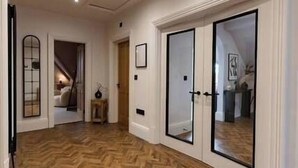 A hallway with wooden flooring, white walls, and a door with glass panels. - Longshaw Loft - Family 3 Bed Apt WiFi & Parking (Buxton)