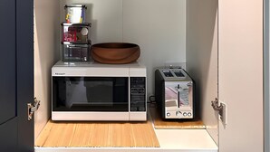 A kitchen with a microwave, toaster, and various dishes and utensils.