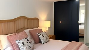 A neatly made bed with a wooden headboard, multiple pillows, and a bedside lamp.
