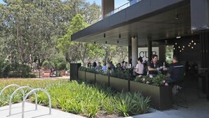 An outdoor seating area with a modern design, surrounded by greenery and trees.