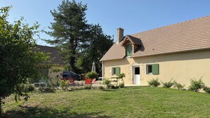 Uma casa com telhado de telhas, chaminé e porta com persianas.
