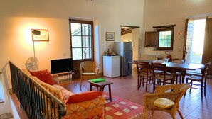 Ein Wohnzimmer mit einer Couch, Fernseher und einem Essbereich mit Stühlen und einem Tisch.