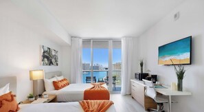 A hotel room with a bed, a desk, a chair, a TV, and a window with a city view.