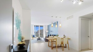 Un salon moderne avec un coin repas, de grandes fenêtres et une vue sur la ville.