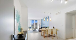A modern living room with a dining area, large windows, and a view of the city.