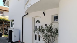 Un bâtiment blanc doté d’un balcon, d’une porte et d’une plante en pot.