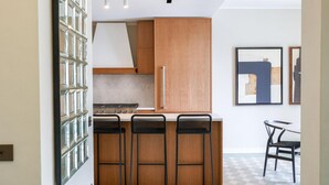 Una cocina con armarios de madera, estufa y tres taburetes negros.