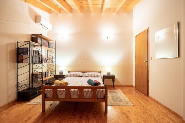A bedroom with a wooden bed, a bookshelf, a desk, and a wardrobe.