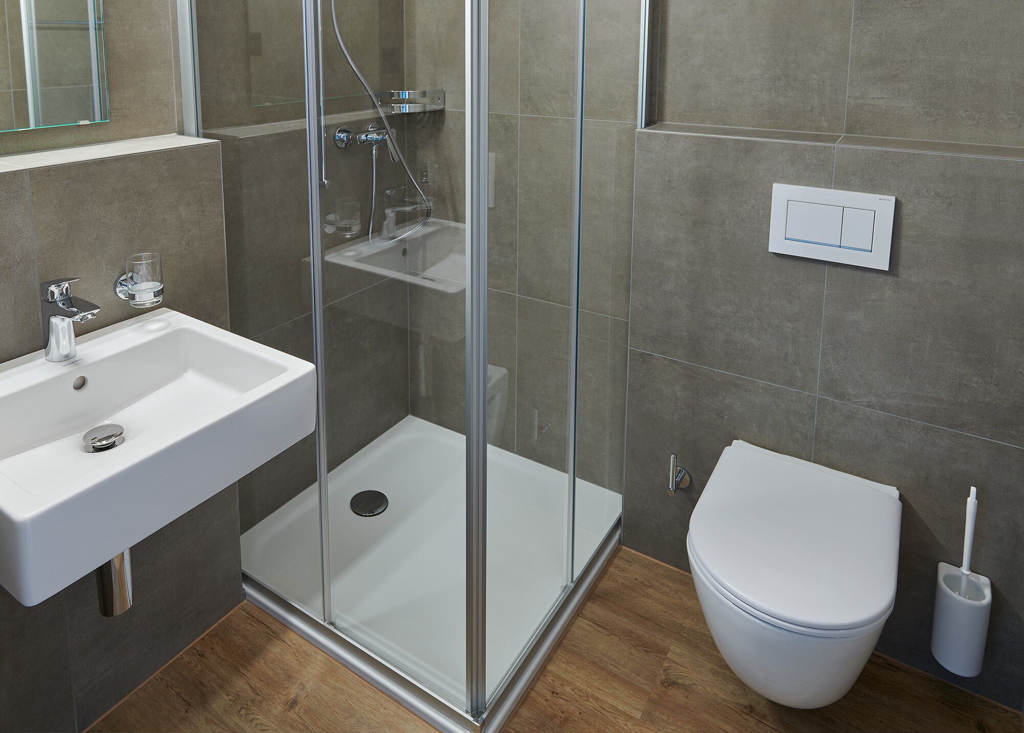 Un baño moderno con ducha de vidrio, lavamanos blanco y retrete.
