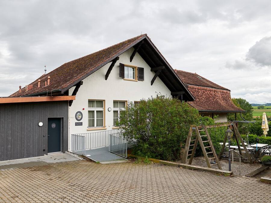 A traditional building with a sloped roof, a reception desk, and a paved entrance area.