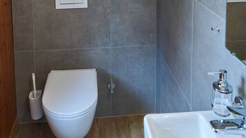 A modern bathroom with a white toilet, a sink, and a mirror.