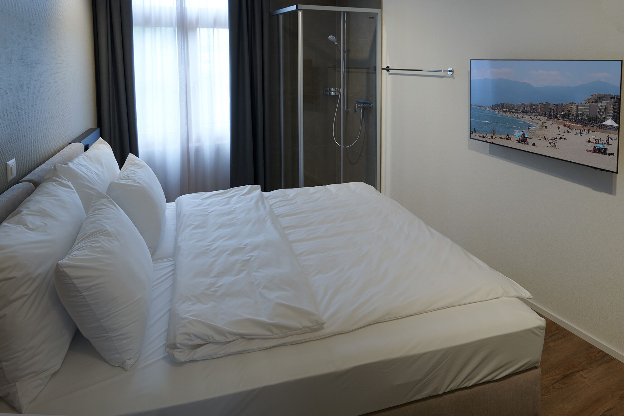 Habitación de hotel con cama, ducha y un cartel con vista a la playa.