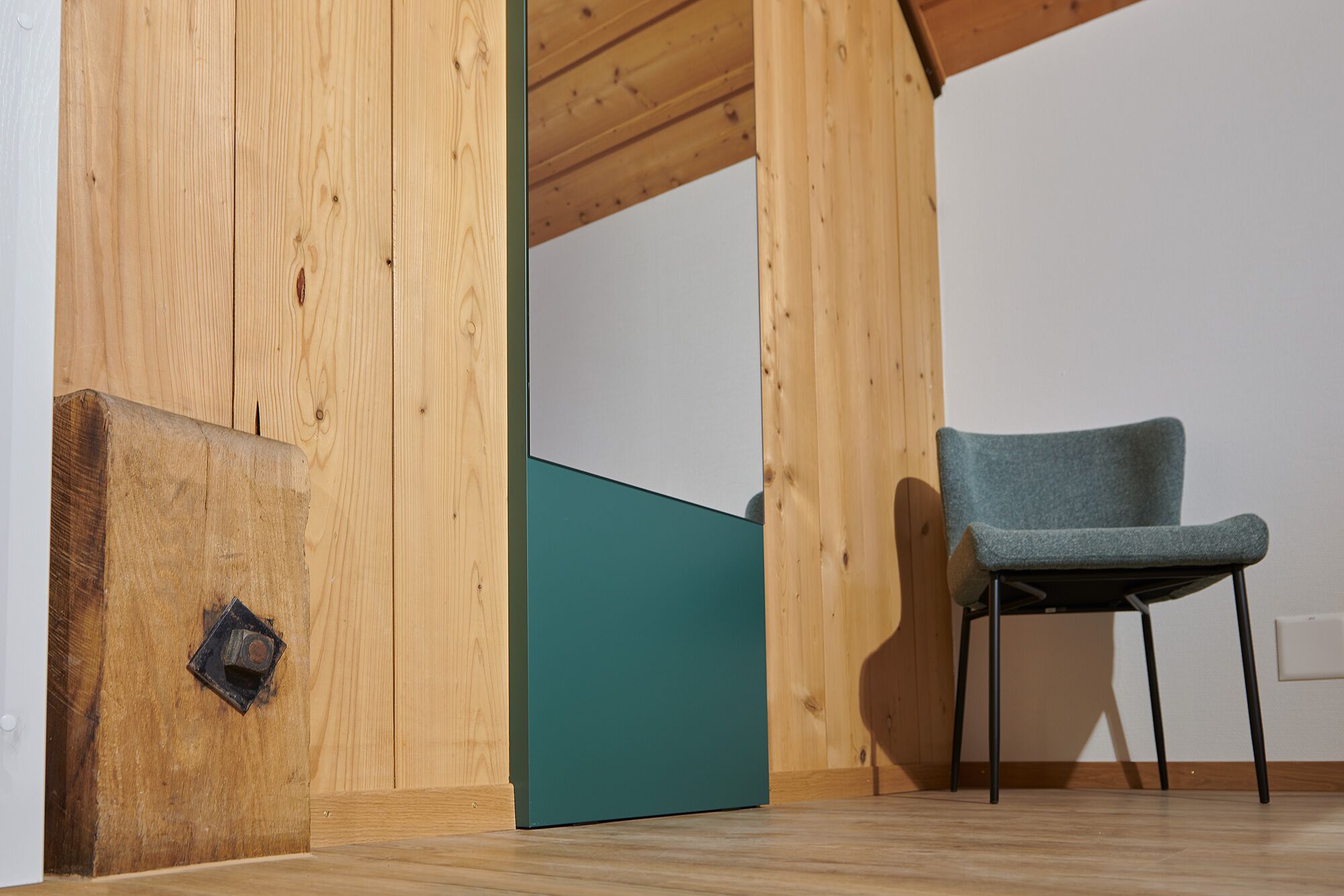 Ein Zimmer mit Holzwänden, einer türkisfarbenen Akzentwand und einem Stuhl.