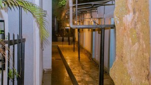 A corridor with a tiled floor, metal railings, and a large rock-like structure on the right. - Boutique Hotel Rwanda (Kigali)