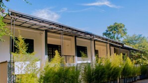 A row of hotel rooms with a covered walkway and potted plants in front. - Boutique Hotel Rwanda (Kigali)