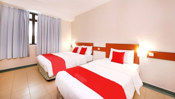 A hotel room with two beds, each with white and red bedding, a large window with curtains, and a tiled floor. - Hotel Famous Inn (Malacca City)
