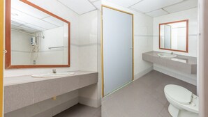 A modern bathroom with a large mirror, a sink, and a toilet. - Hotel Famous Inn (Malacca City)
