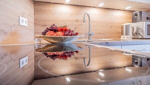 Eine moderne Küche mit Holzrückwand, Edelstahlgeräten und einer glänzenden Arbeitsplatte.