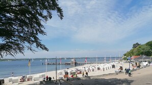 Eine Uferpromenade mit Sitzgelegenheiten, einem Steg und Flaggen.