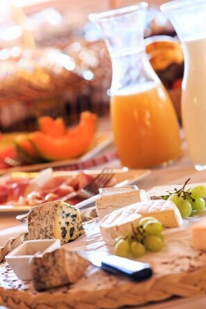 A cheese board with various cheeses, grapes, and a pitcher of orange juice. - Hotel Blanche Neige   (Courchevel)