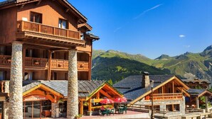 A wooden building with balconies and a restaurant area with outdoor seating. - Hotel Blanche Neige   (Courchevel)