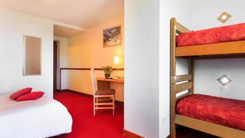 A room with a bunk bed, a desk with a chair, a small table with a plant, and a painting on the wall.